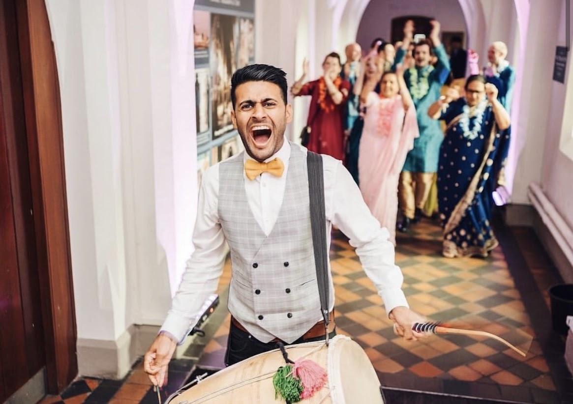 An Asian wedding musician playing a drum at an Indian wedding