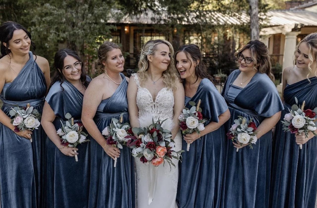 bride smiling next to her bridesmaids wearing grey velvet dresses