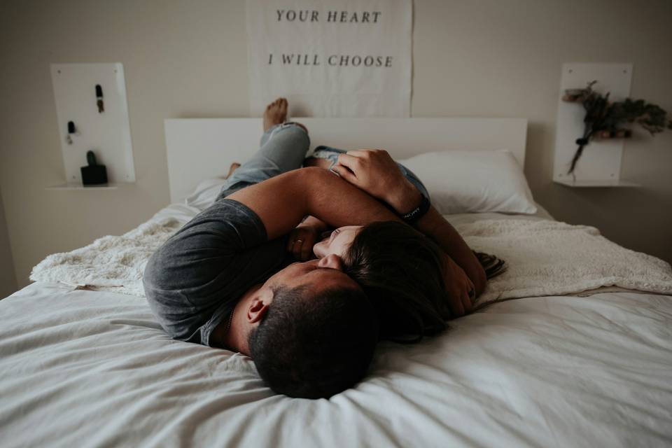 Man and woman lying on the bed cuddling and laughing