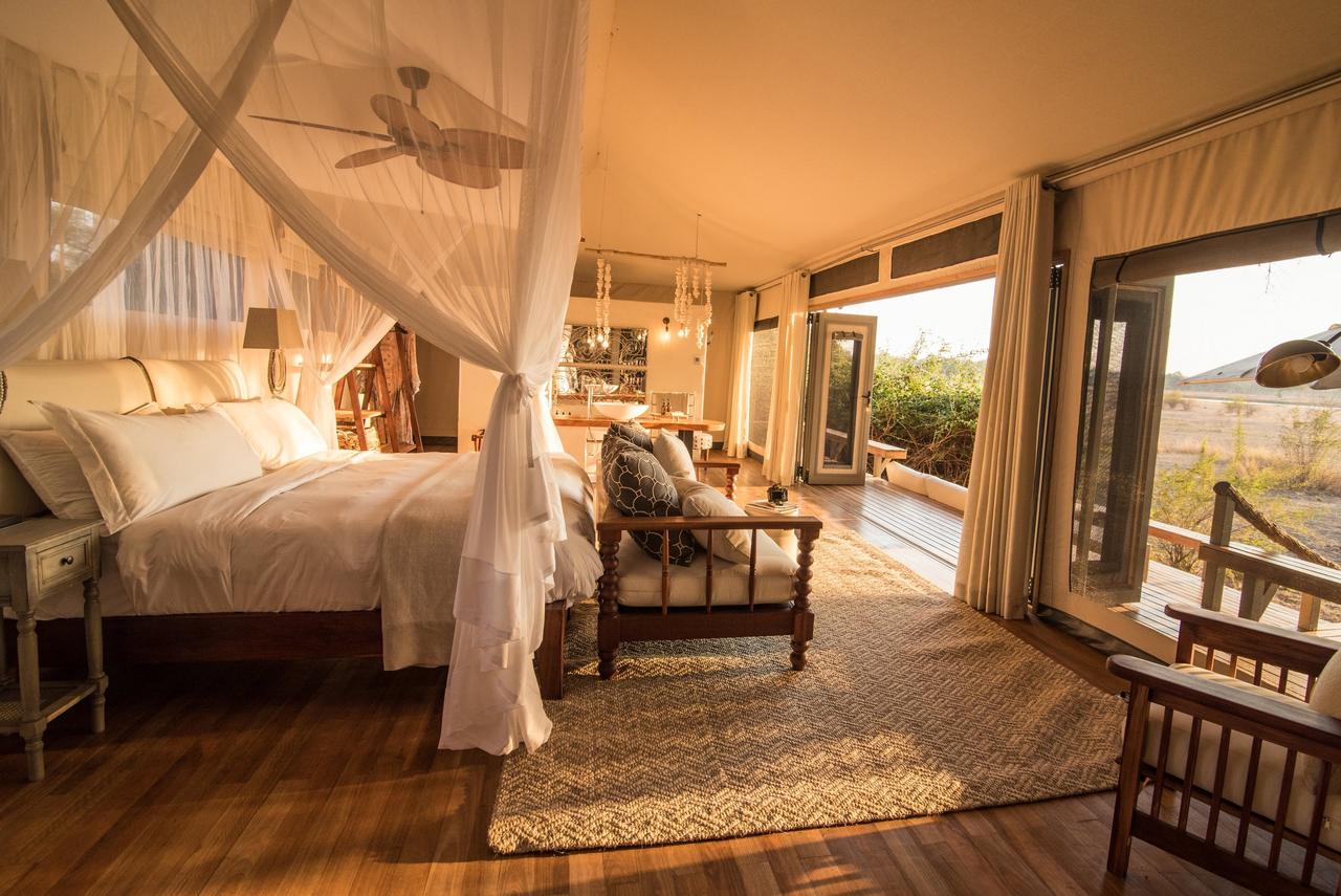 A four-poster white bed in a luxurious hotel room, part of the Chikwenya Mana Pools hotel in Zimbabwe