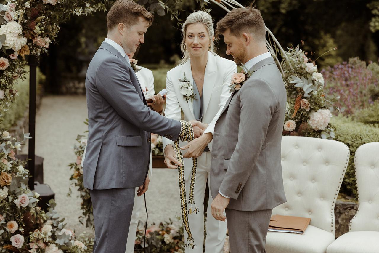 The grooms' hands are tied for the handfasting