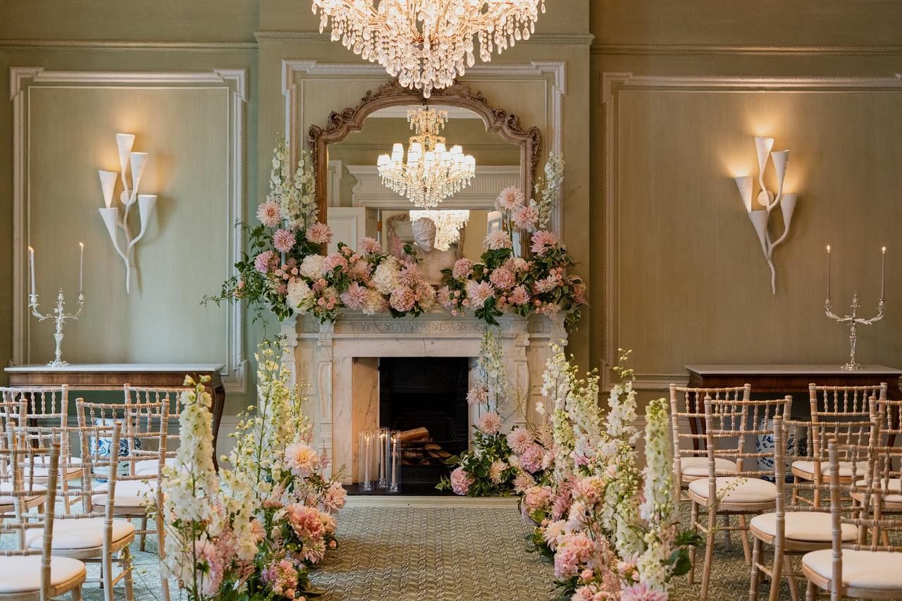 beautiful cream green event space in the browns hotel with white chairs and a fireplace covered in flowers