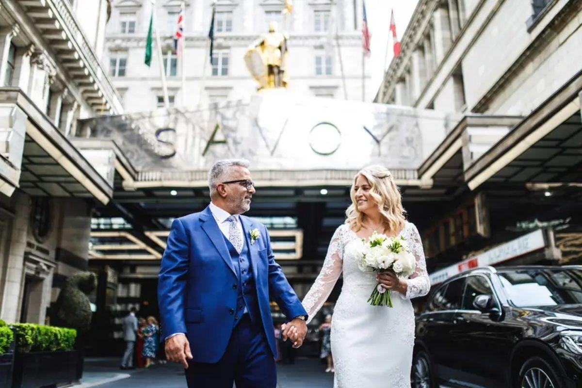 a couple holding hands as they walk out of the Savoy hotel in london after a city wedding