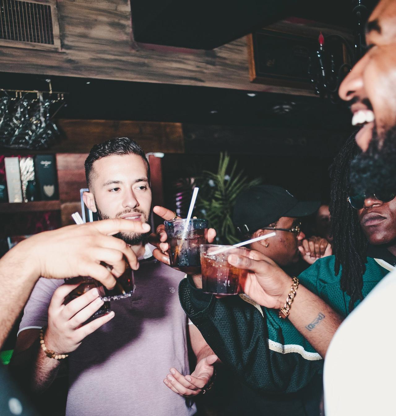 A group of stags in a bar cheersing their drinks and dancing to music