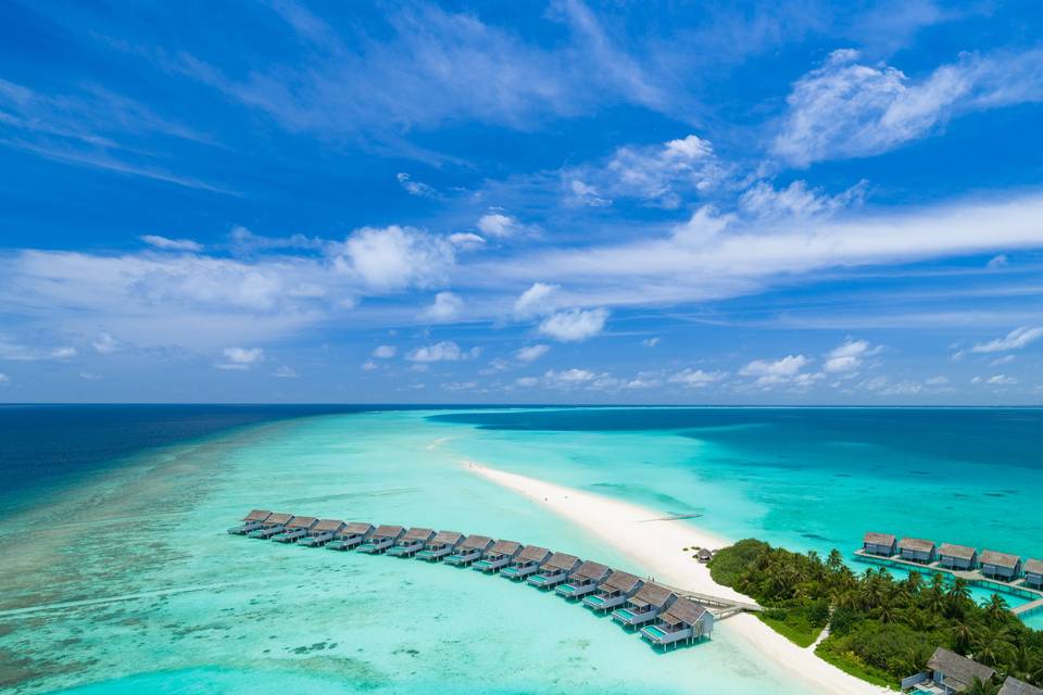 An areal shot of Kuramathi Island with overwarer bungalows, white sand and turquoise waters