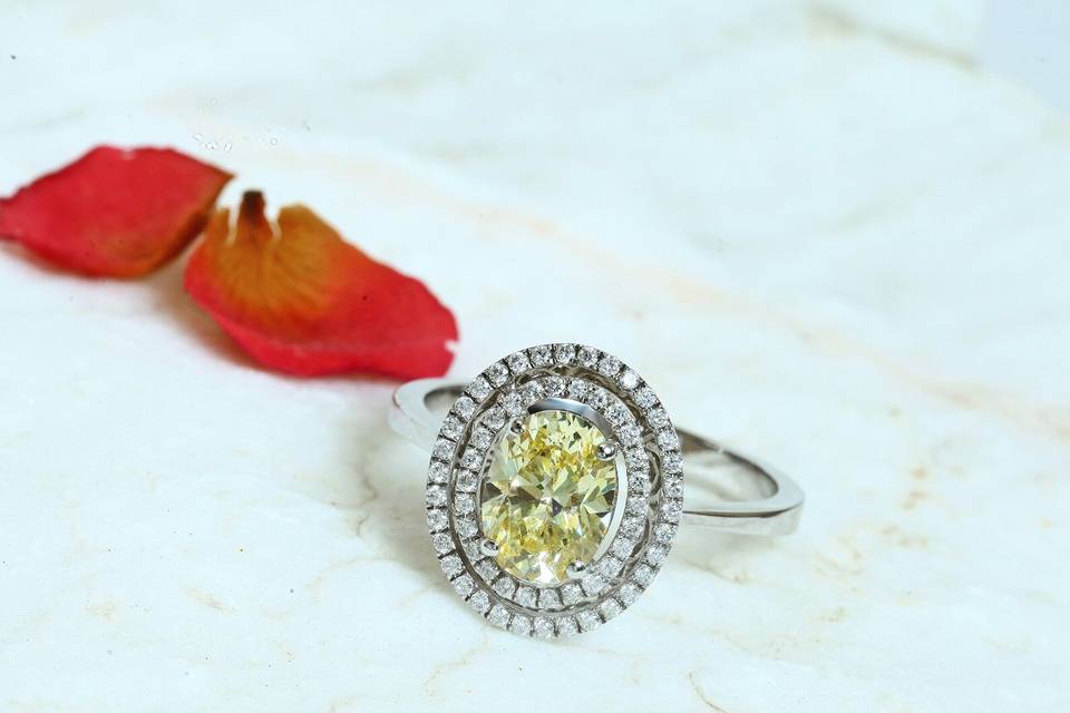 An oval double-halo engagement ring with yellow centre diamond on a white gold band