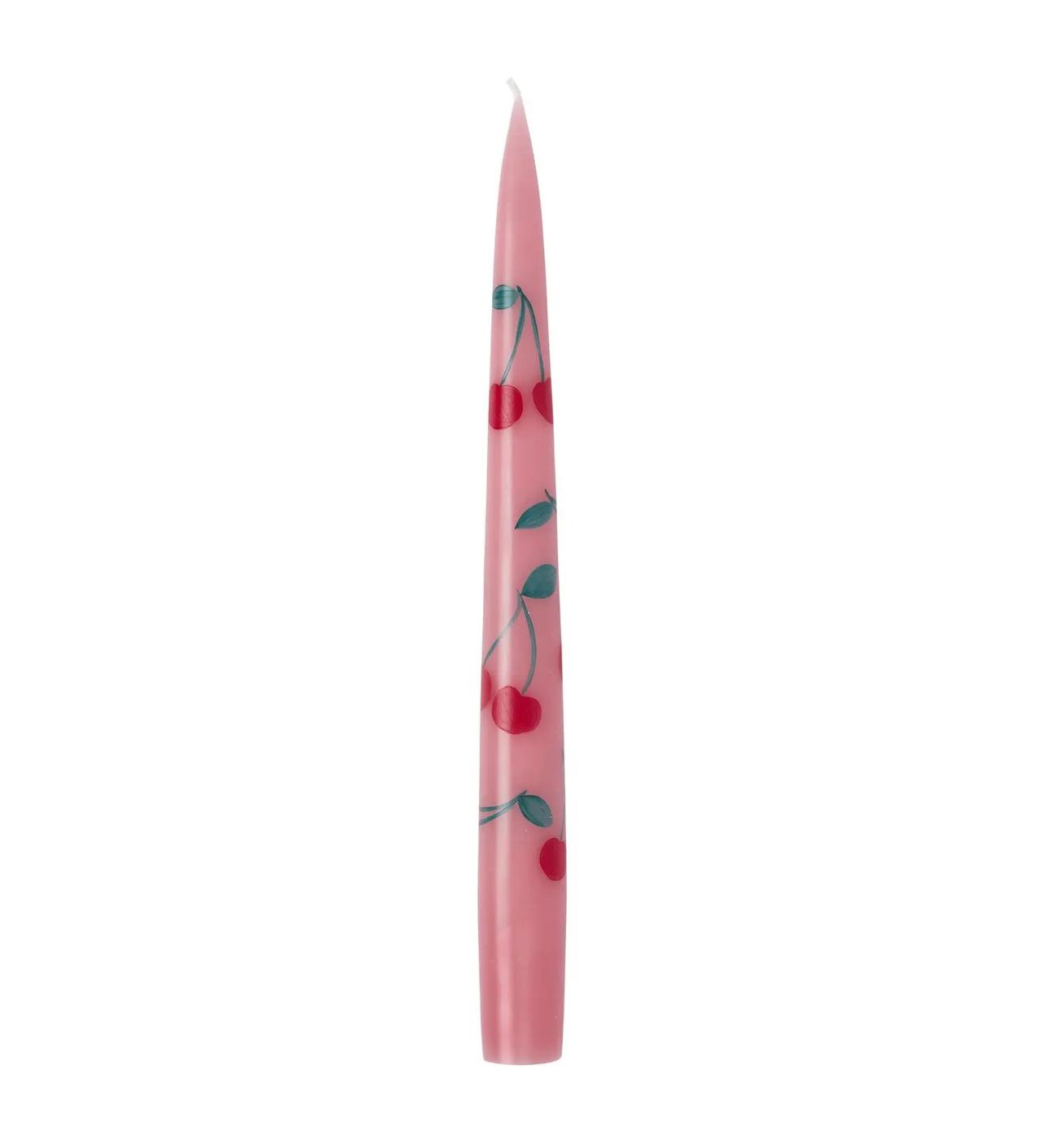 A pink tapered candle with a handpainted cherry print on a white background.