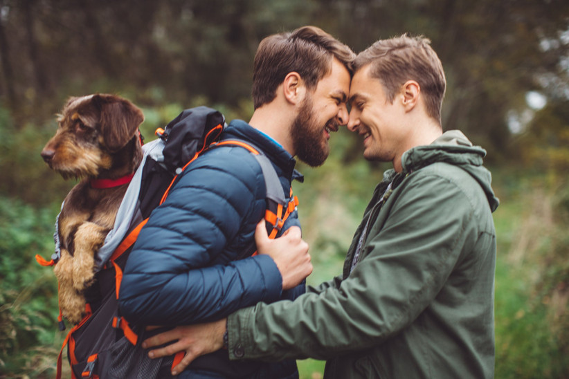 Coppia gay che porta a spasso il cane, celebrando il matrimonio e l'anniversario