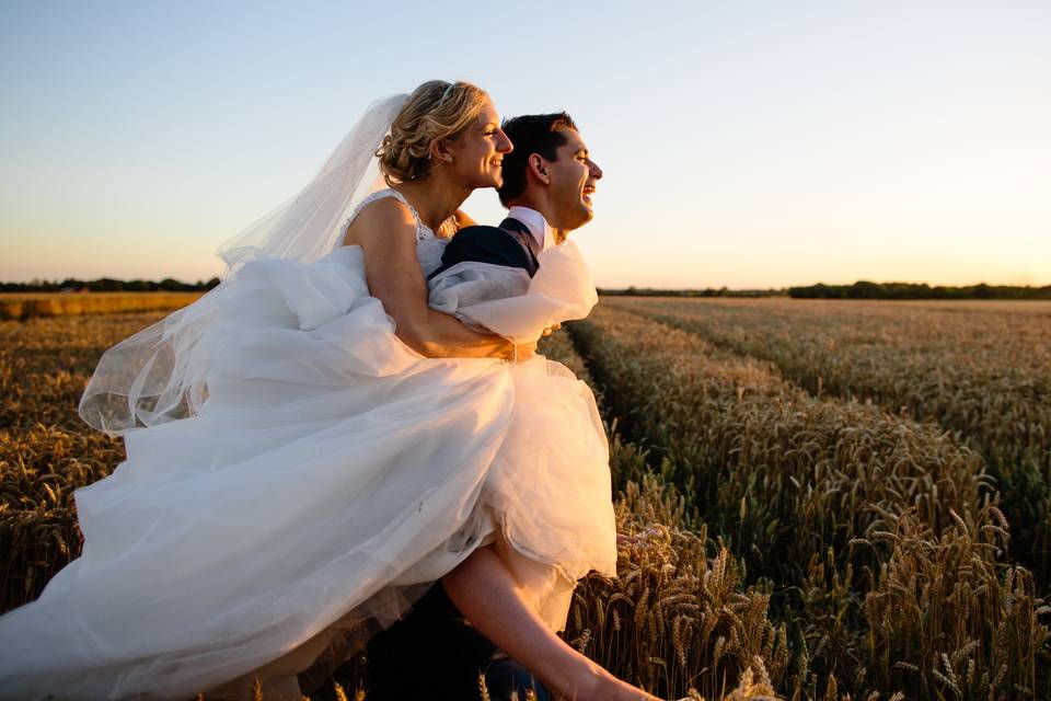 Bride and groom in a field at sunset
