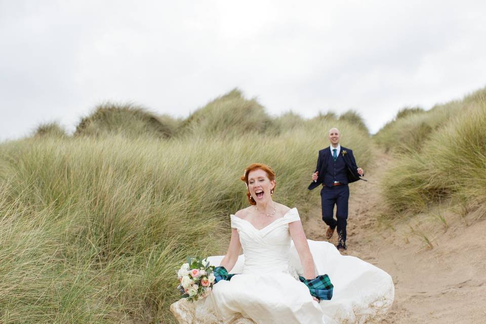 Bride runs down hill in sand