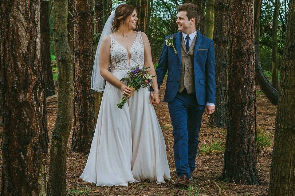 Bride and groom walk in woods