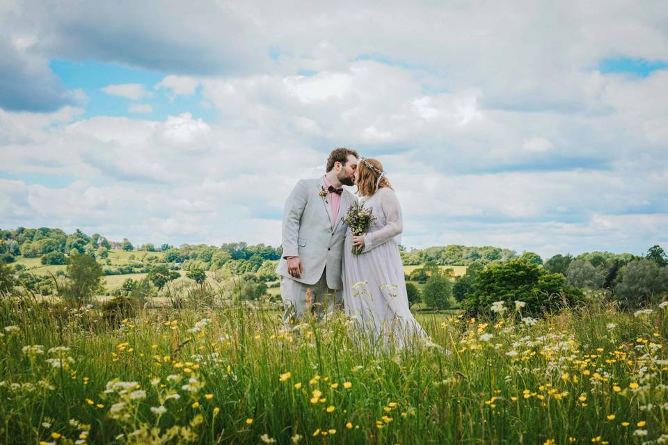 Bride and groom kiss in meadow