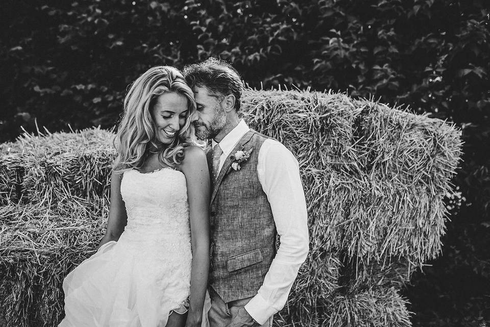 Newlyweds in front of stacks of hay