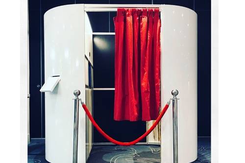 Enclosed DJ booth with red curtain and rope