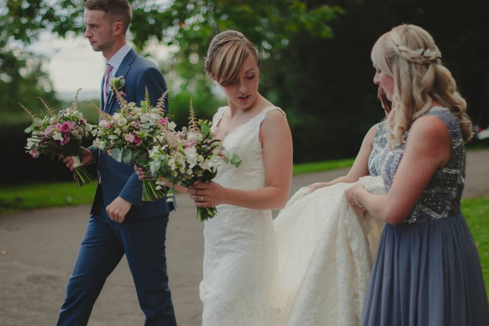 Bridesmaid holds up dress