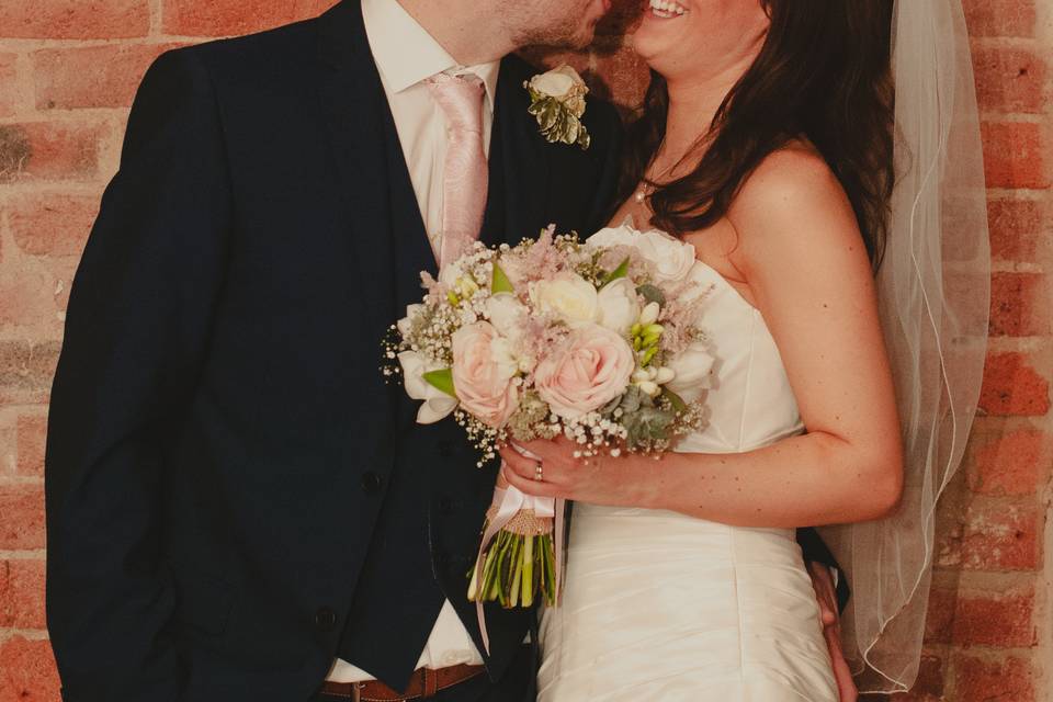 Bride and groom on brick wall