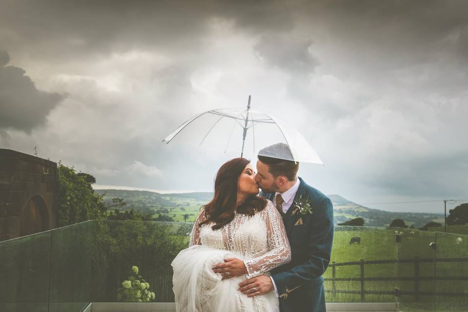 Couple standing under an umbrella - Jon Thorne Weddings