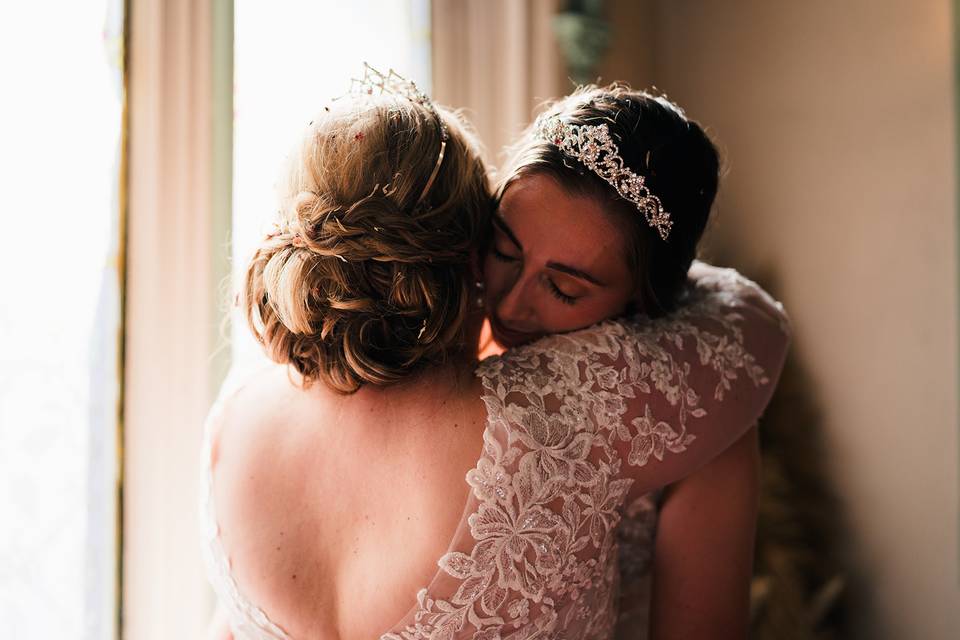 Two brides hug by the window