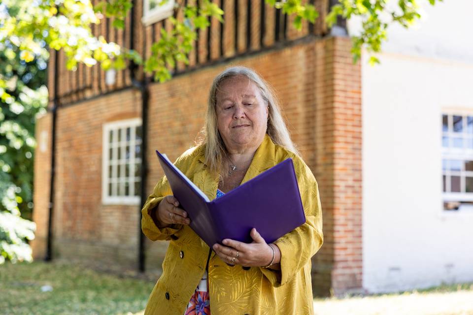 Celebrant by white building with folder