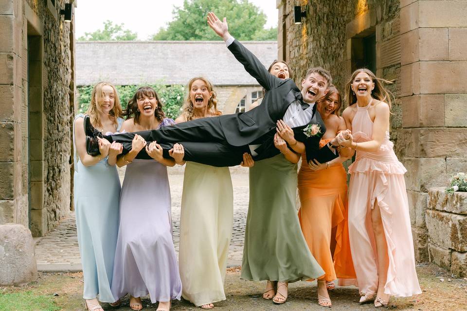 Groom held by bridesmaids
