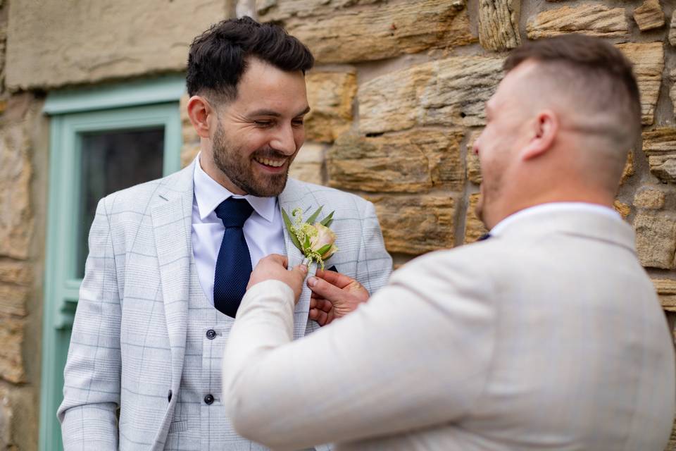 Smiling and placing buttonhole on suit