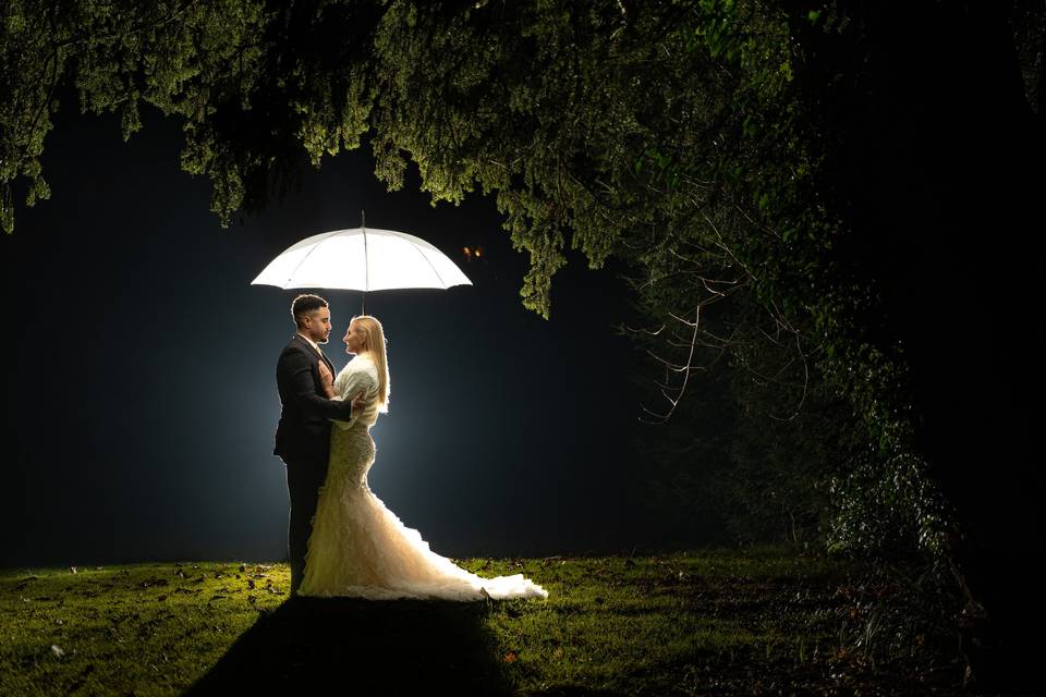 Bride and groom under umbrella