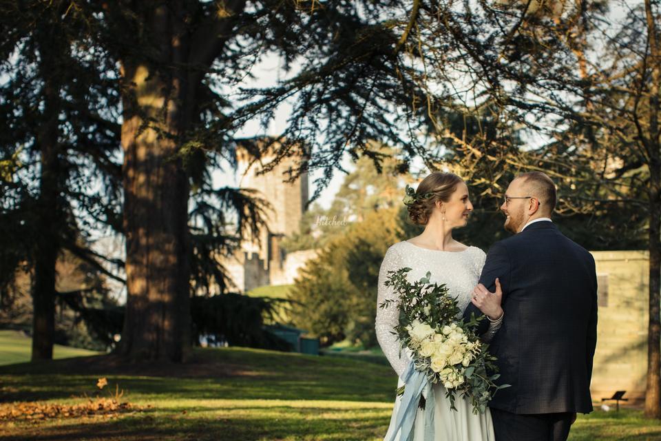 A bride and groom standing facing opposite ways staring at each other with the turrets of Warwick Castle in the background