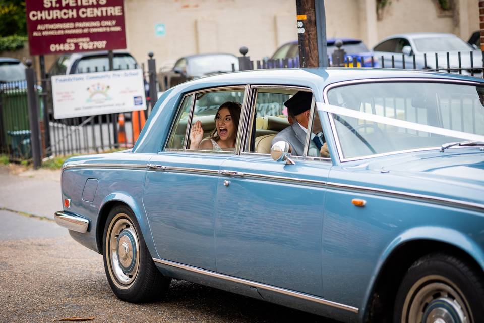 Bride waving in wedding car