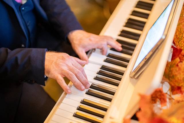 close up pianist hands playing white piano with tablet
