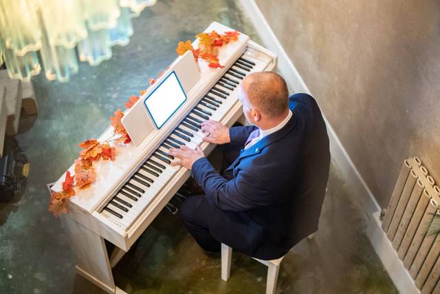 elevated angle pianist playing upright piano by stairs