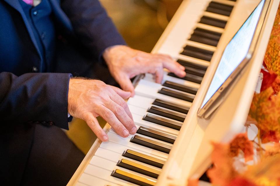 close up pianist hands playing white piano with tablet
