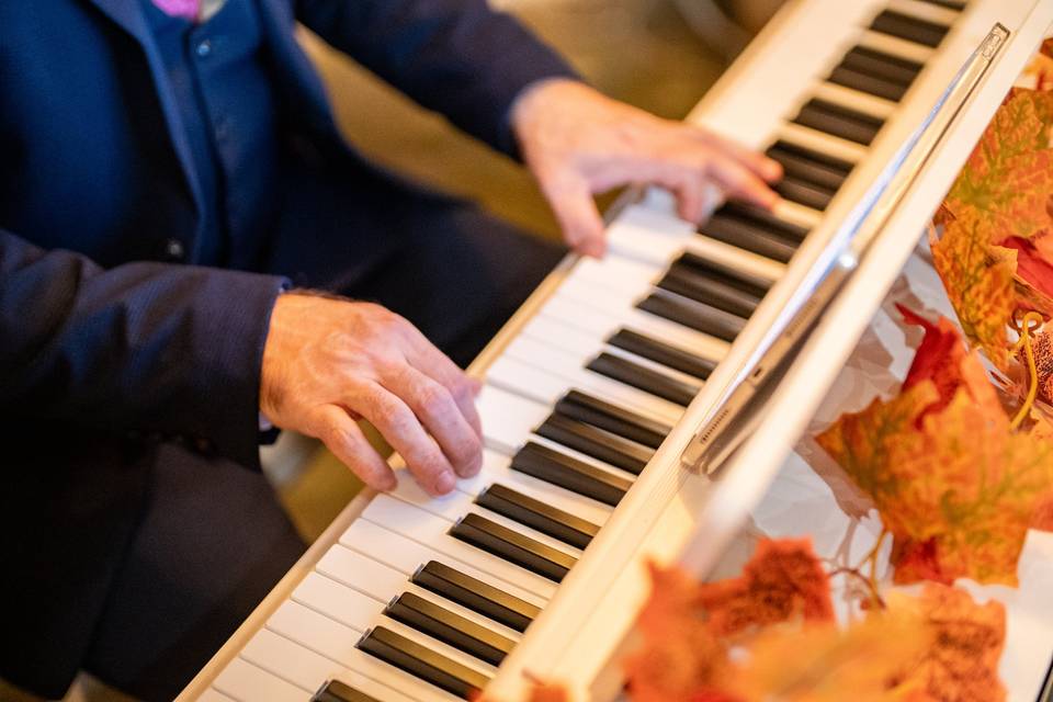 detail shot pianist hands on keyboard with autumn decor