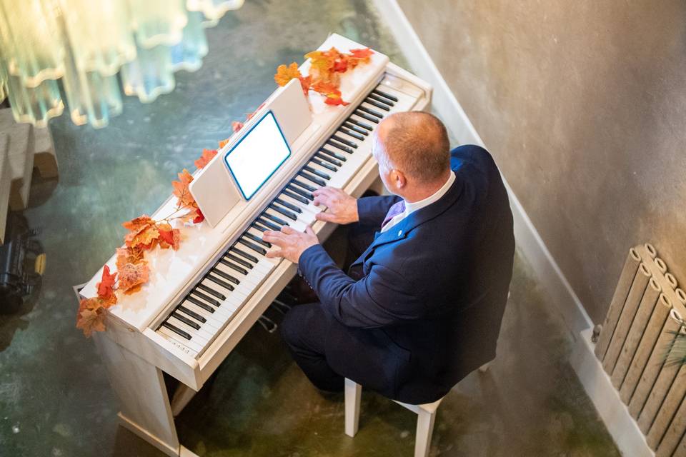 elevated angle pianist playing upright piano by stairs