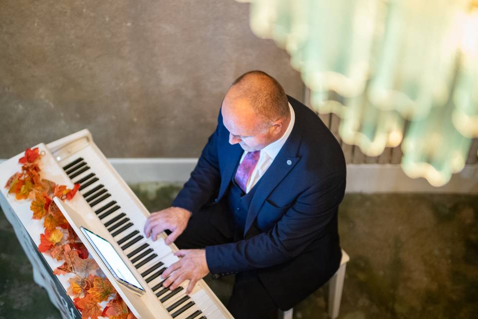 pianist performing at white upright piano