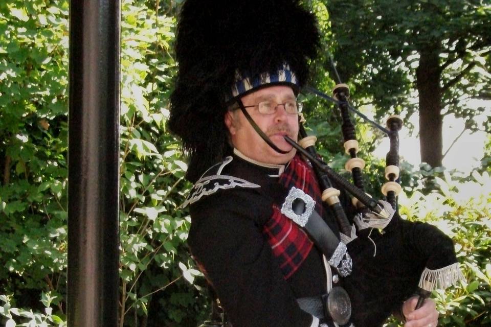 A piper welcomes the guests from the gazebo