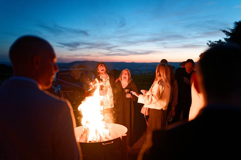 Guests laugh around the fire