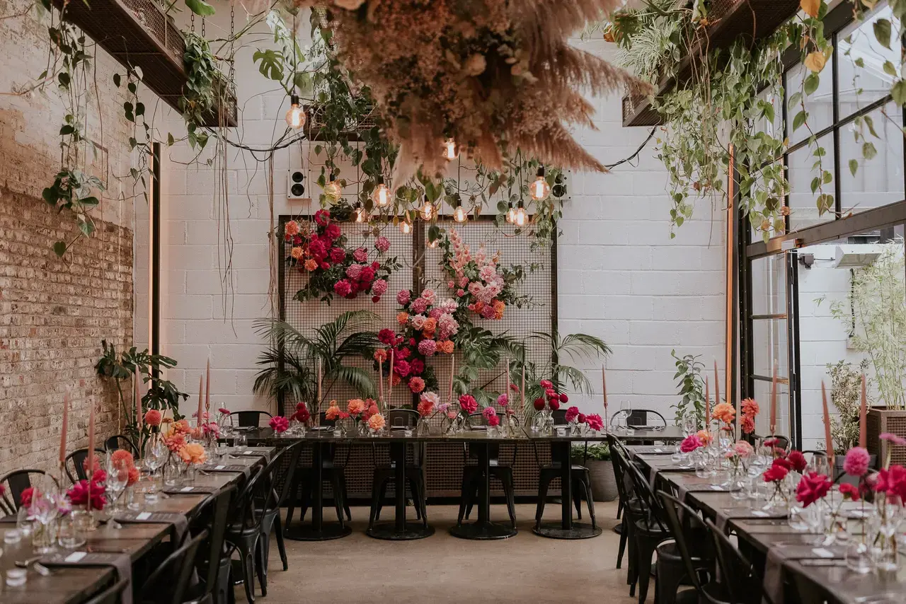 Interior shot of The Hackney wedding venue with wild hanging flowers and pink rose centrepieces 