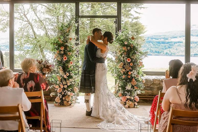 Couple kiss by floral arch