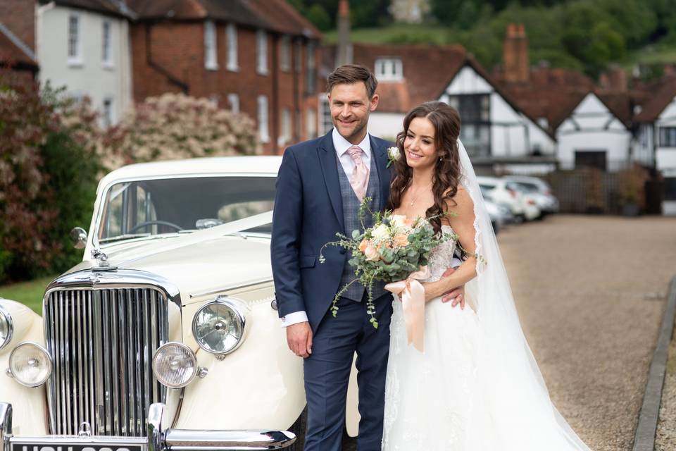 Couple standing in front of a classic car