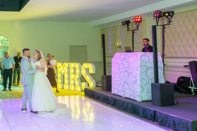 bride and groom dancing under green event lights
