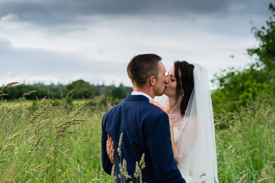 Bride and groom kissing in grass