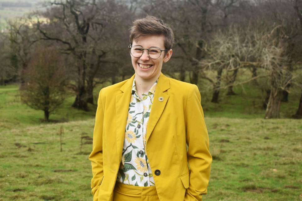 Tee laughing in a yellow suit
