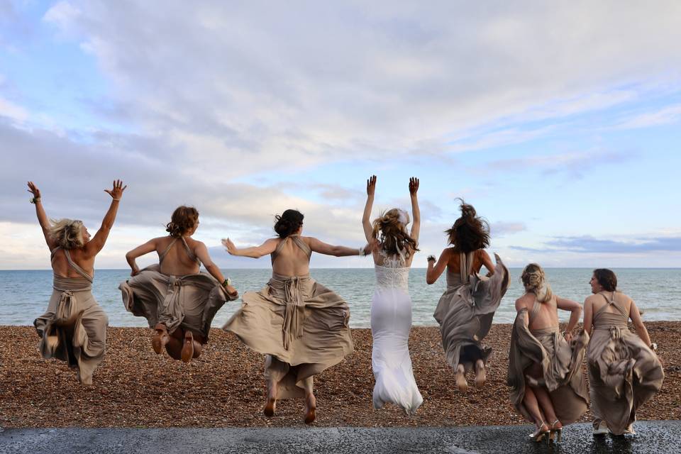 Bridesmaids jumping on the bea
