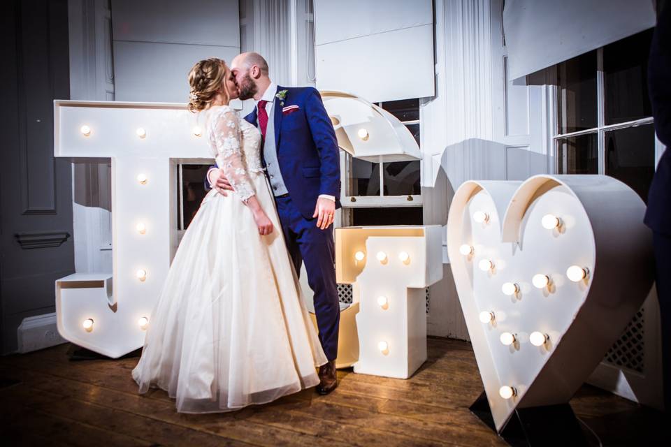 Newlyweds in front of light up initials