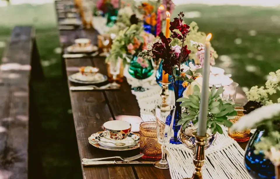 Wedding tablescape set up with mismatched coloured vases, macrame table runner and vintage style plates